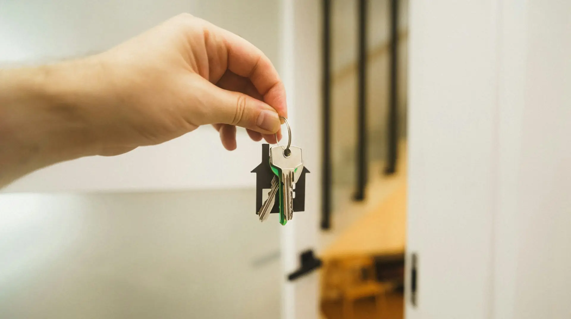 A hand holding a house key at an open front door