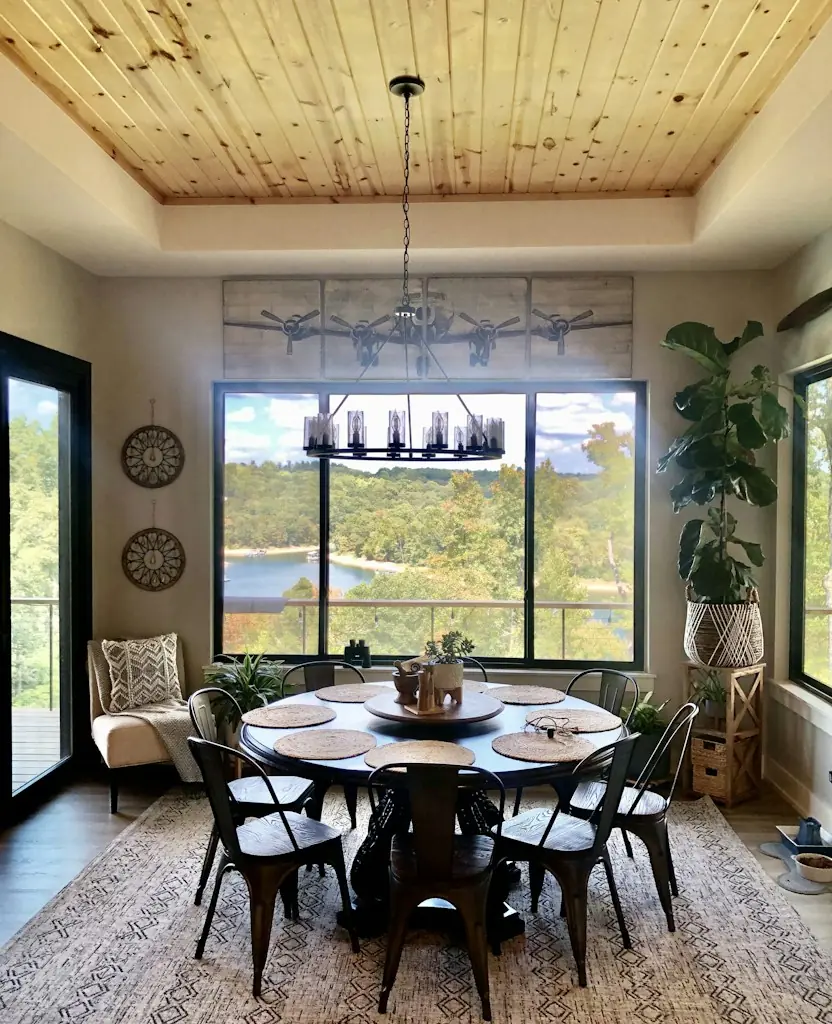 A round dining table under a window with a view of the water